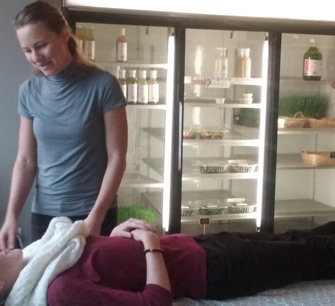 Student Therapist works on a participant lying on a massage table with massage therapy.  Nourish Juice & Advanced Therapy Institute of Touch love to collaborate.