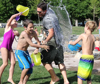 Children & Man Having A Water Fight In The Park | Advanced Therapy Institute of Touch, Colorado Springs