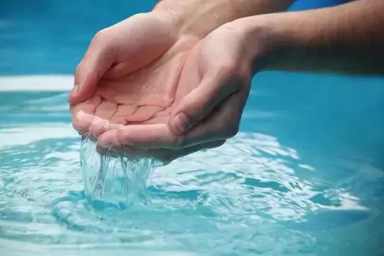 Water streaming from gentle hands creating ripple effects