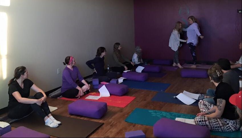 Kim M. Green, Founder, Advanced Therapy Institute of Touch works on co-teacher Terri Long to show community members sitting in a large yoga room how to practice self-care on themselves.